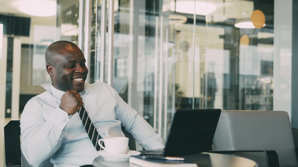Man in shirt and tie laughing at desk