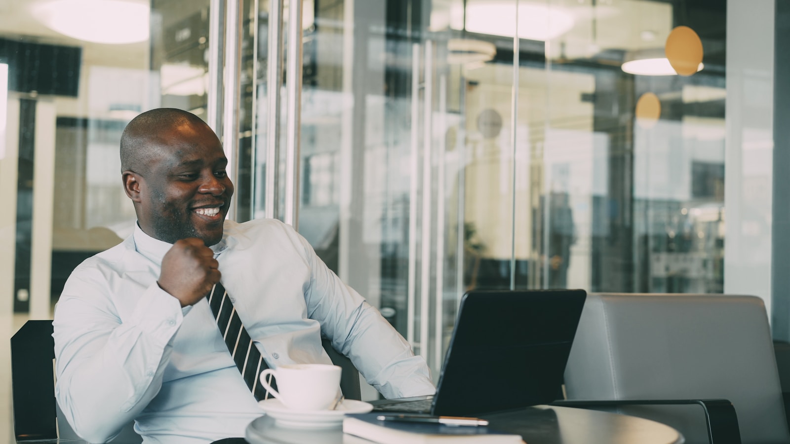 Man in shirt and tie laughing at desk